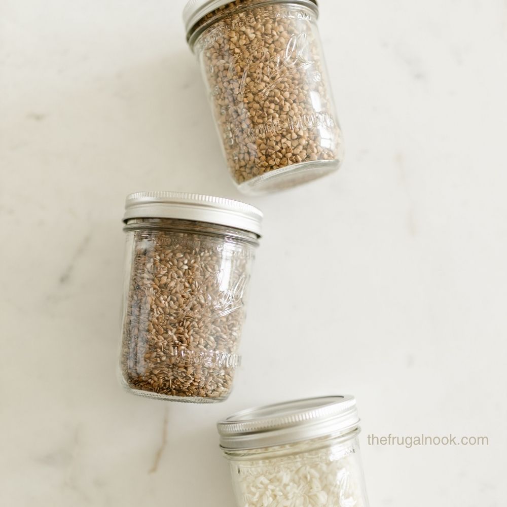 Glass mason jars filled with rice, oats, and grains on a marble counter for the frugal blog