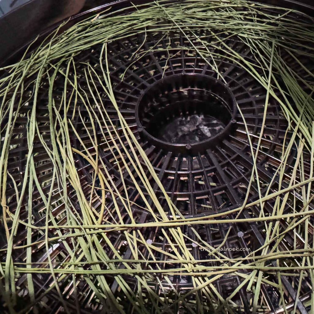 Long thin strands of chives drying on a black dehydrator tray