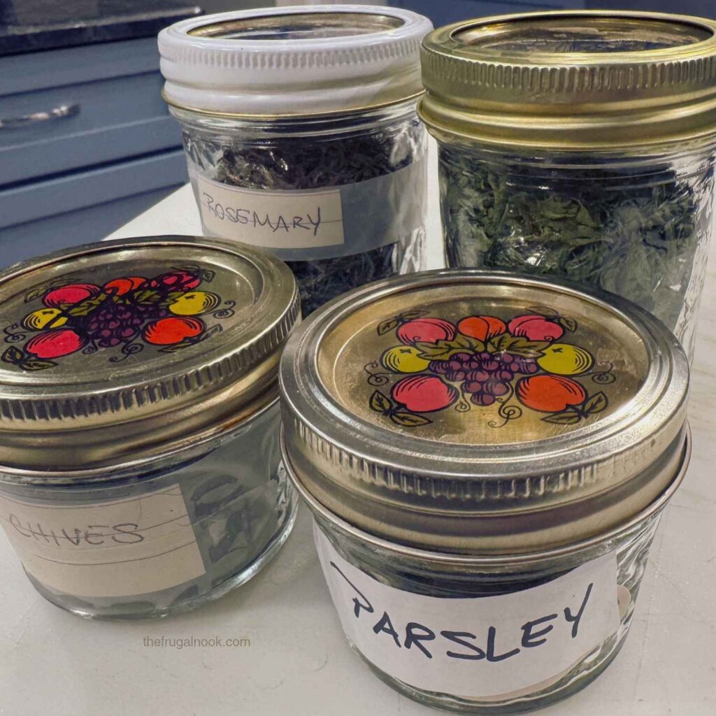 Chives, parsley rosemary and basil dried and stored in glass mason jars.