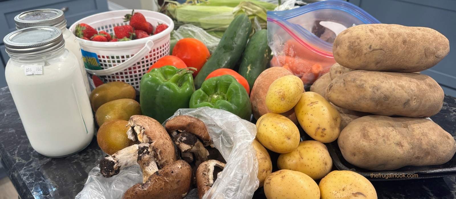 Farmers market grocery store haul with goat milk, strawberries, corn, potatoes, peppers, and mushrooms on a kitchen counter
