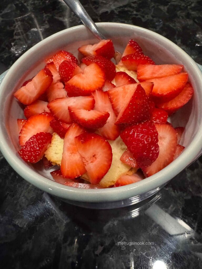 Bowl of sliced fresh strawberries over a slice of pound cake
