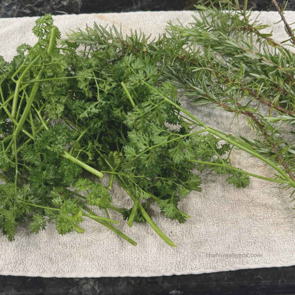 Fresh rosemary, parsley, basil, and chives laid out on a clean towel to dry after washing