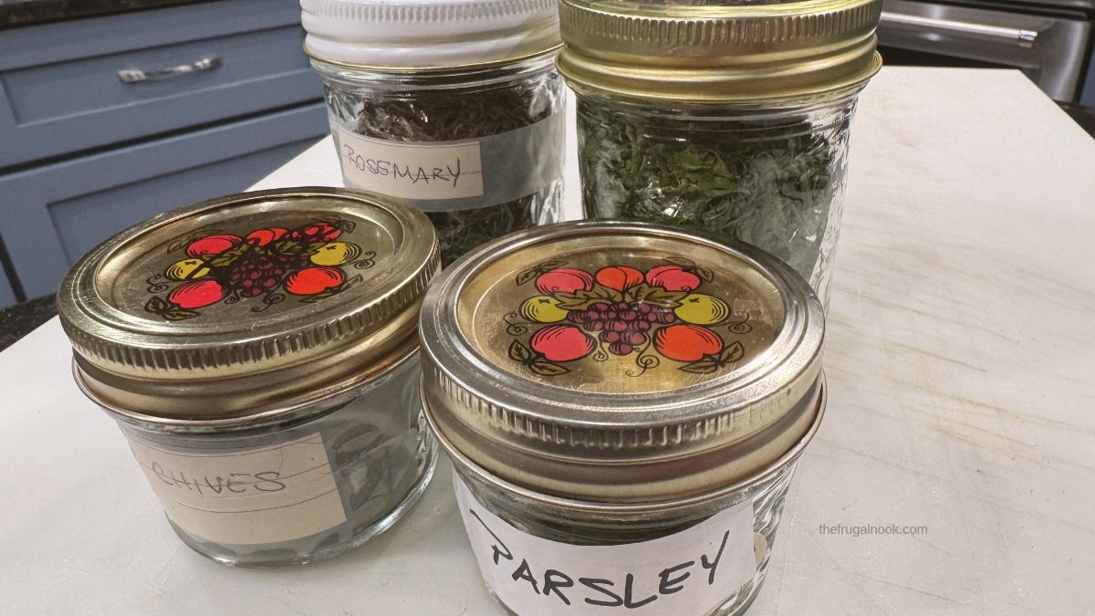 Glass mason jars filled with dried rosemary, parsley, basil, and chives